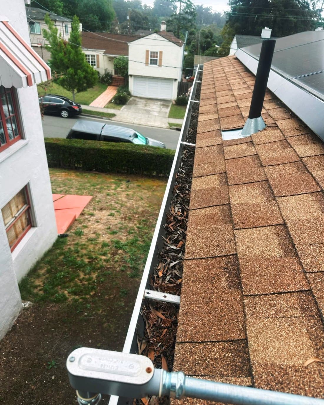 Roof gutter packed with fallen leaves and needles